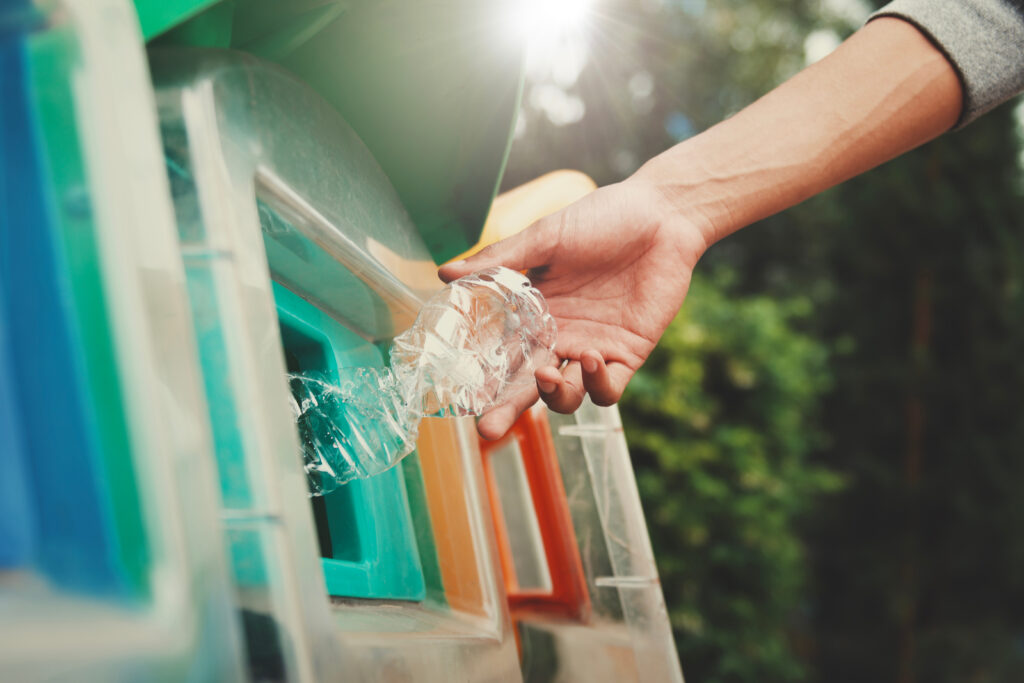 people putting plastic bottle in to recycle bin representing simpler recycling 2027